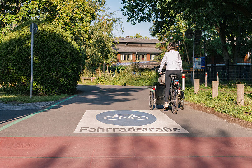 Lastenradfahrerin fährt auf einer Fahrradstraße