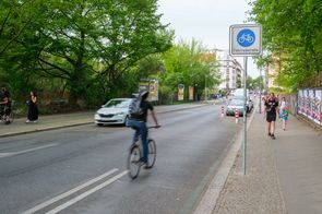 Radfahrende auf Fahrradstraße mit rotweißen Pollern.