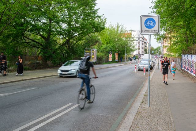 Radfahrende auf Fahrradstraße mit rotweißen Pollern.