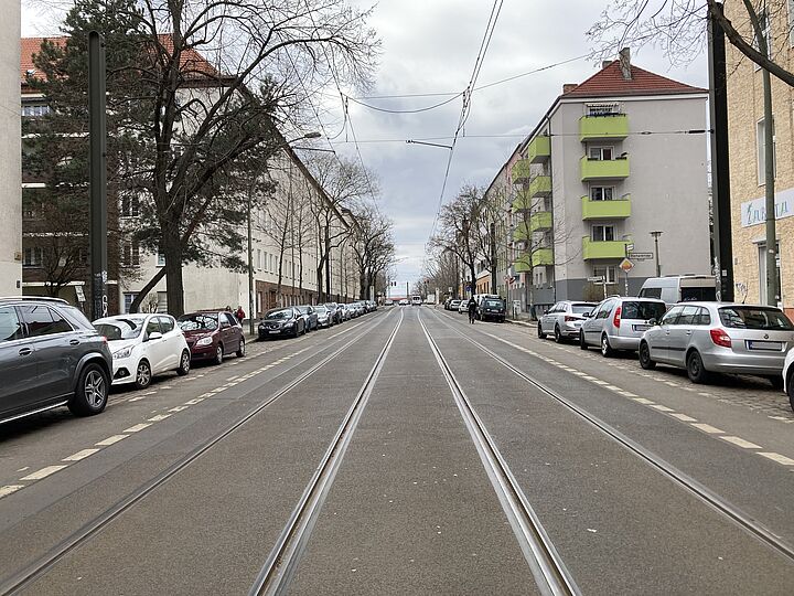 Straße mit Tram-Schienen und parkenden Autos am Straßenrand