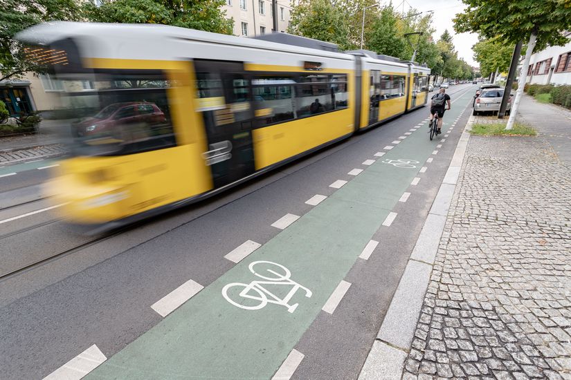 Fahrradfahrer fährt auf Grünmarkierten Radweg, parallel zur Straßenbahn