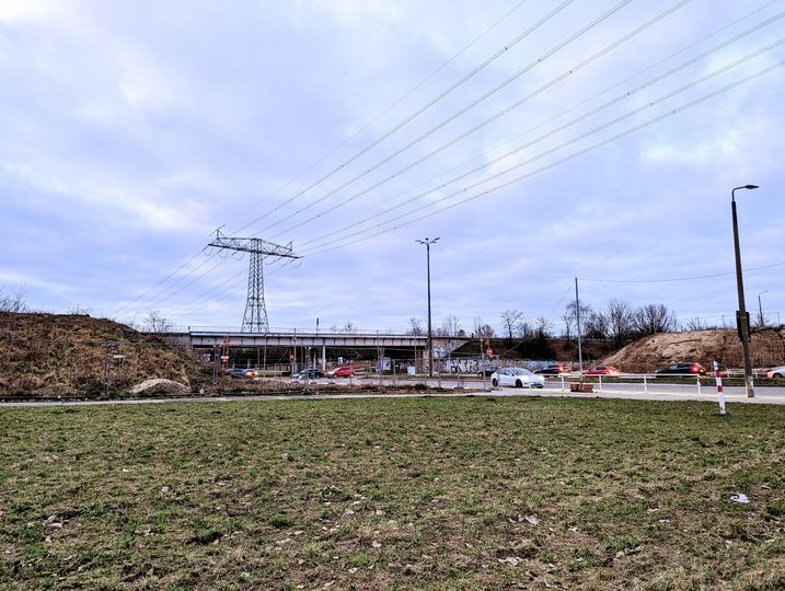 Blick auf eine alte Brücke in der Ferne, im Vordergrund grüner Rasen