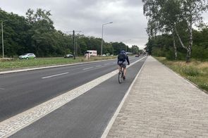 Radfahrer fährt auf einem Hochbordradweg rechts neben der Straße