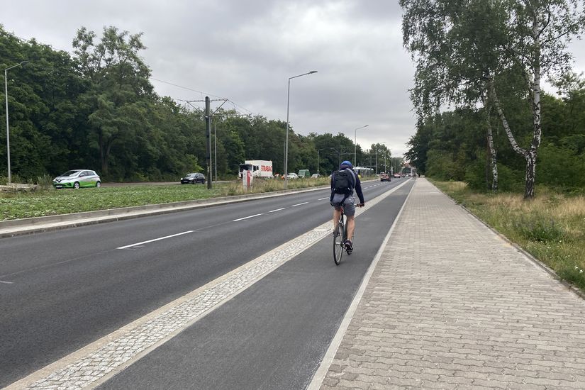 Radfahrer fährt auf einem Hochbordradweg rechts neben der Straße