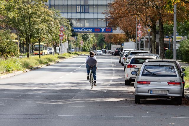 Eine Radfahrerin auf der Sonnenallee nutzt die rechte Fahrspur neben den parkenden Autos