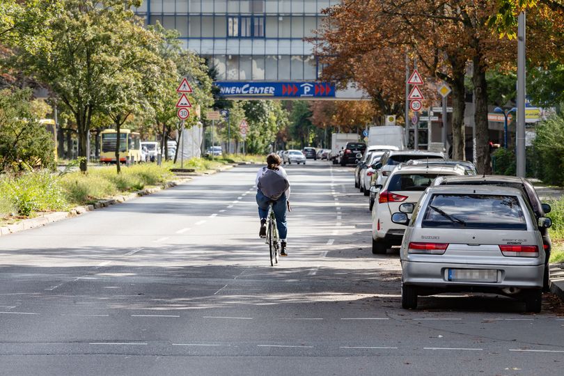 Eine Radfahrerin auf der Sonnenallee nutzt die rechte Fahrspur neben den parkenden Autos