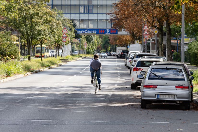 Eine Radfahrerin auf der Sonnenallee nutzt die rechte Fahrspur neben den parkenden Autos