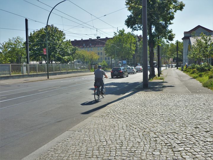 Radfahrer fährt neben Autos auf Siegfriedstraße in Berlin Lichtenberg