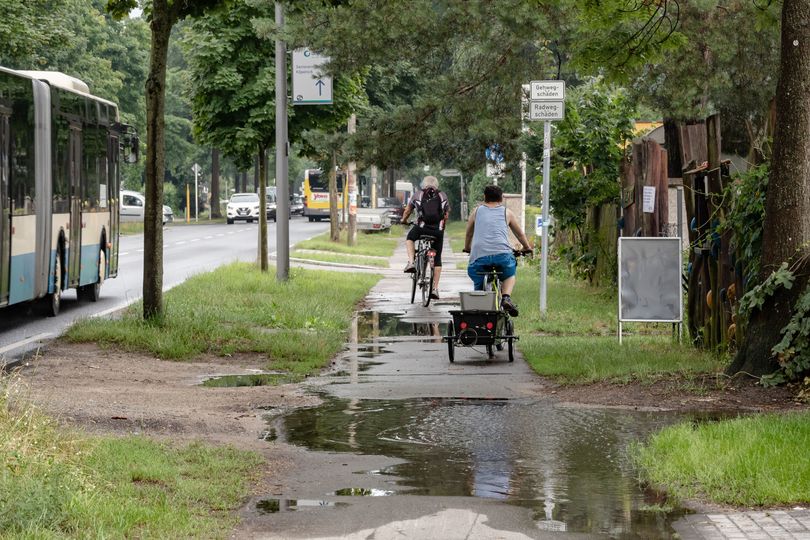 Beschädigter Radweg und Gehweg mit Regenpfützen Fürstenwalder Allee