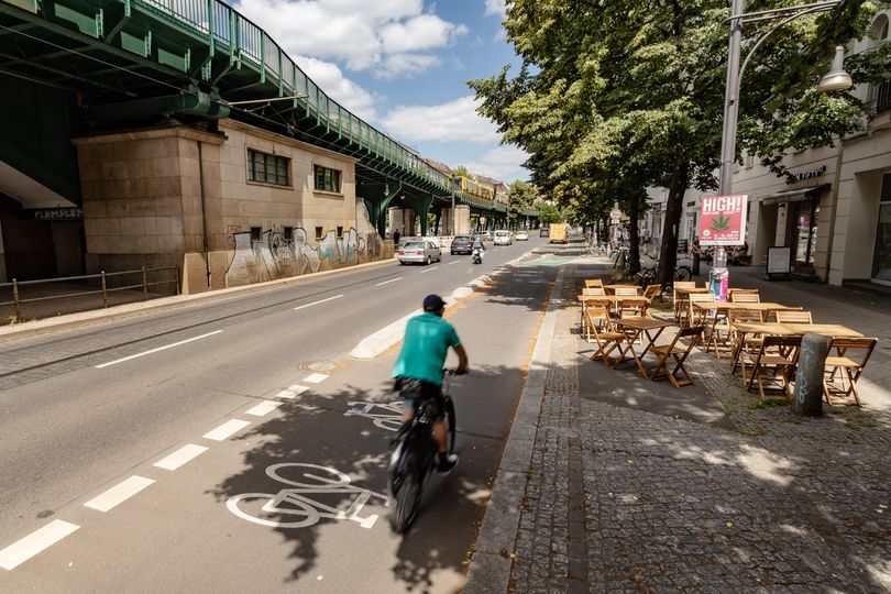 Geschützter Radfahrstreifen auf der Schönhauser Allee. Alte Hochbordrad wird durch Gastronomie genutzt.