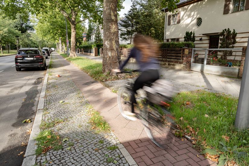 Fahrradfahrer*in fährt auf schmalen Hochbordradweg