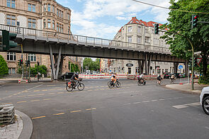 Mehrere Radfahrer fahren auf Radfahrstreifen vor einer U-Bahnbrücke