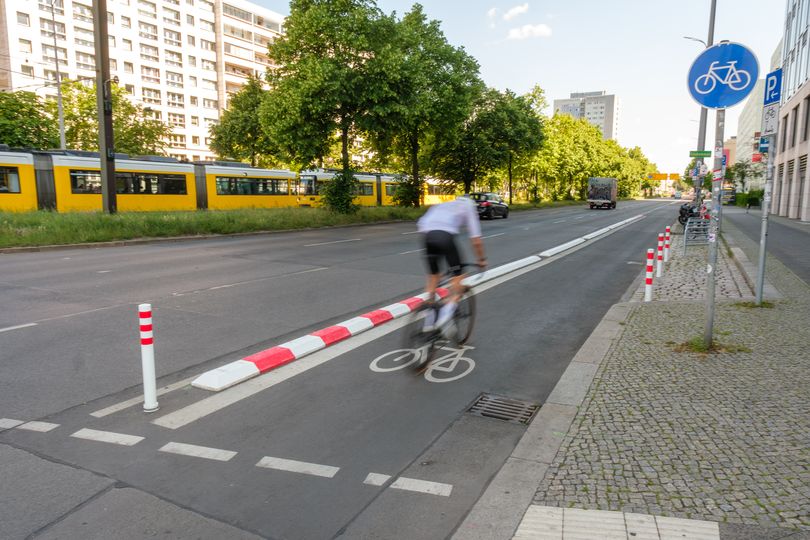 Radfahrer fährt auf geschütztem Radfahrstreifen, im Hintergrund eine gelbe Tram.