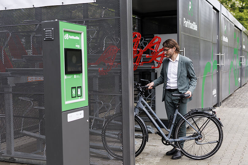 Ein Mann parkt sein Fahrrad in einer gesicherten Sammelschließanlage.