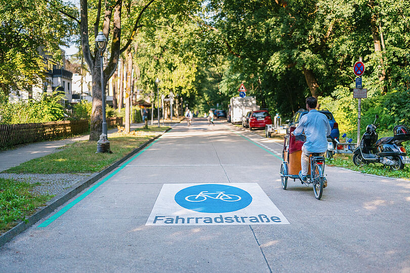 Lastenradfahrer fährt auf einer Fahrradstraße in einer Wohngegend