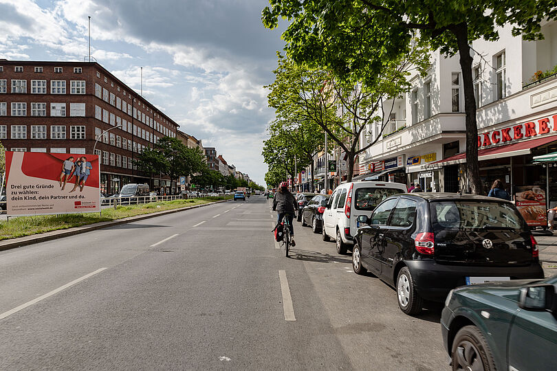 Blick auf die Müllerstraße am Leopoldplatz ohne Infrastruktur für Radfahrende, parkende Autos am rechten Fahrbahnrand