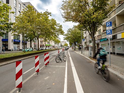 geschützter Radfahrstreifen am rechten Fahrbahnrand, links davon Sperrflächen und Abstellbügel für Fahrräder