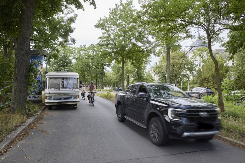 Straßenszene in Berlin mit Radfahrern zwischen fahrenden Autos und parkendem Wohnmobil – fehlende sichere Fahrrad-Infrastruktur
