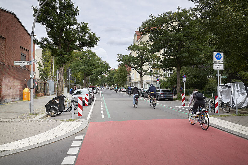 Mehrere Fahrradfahrer fahren auf einer Fahrradstraße. Im Vordergrund ein Kreuzungsbereich, der großflächig rot markiert ist.