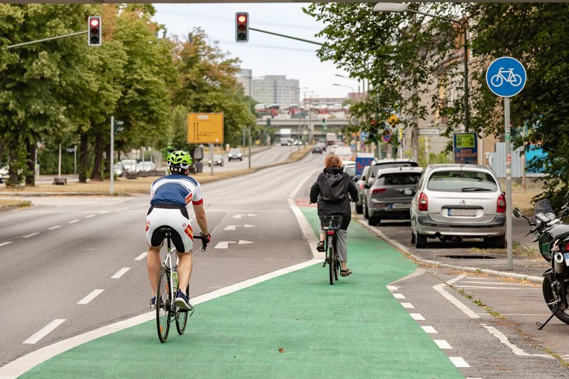Fahrradfahrer auf einer grünbeschichteten Straße vor einer Ampel