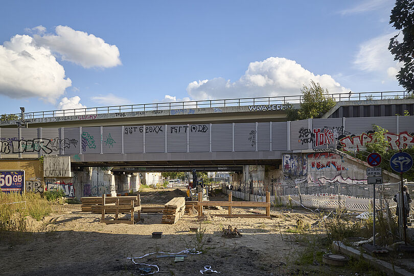Straßenbaustelle mit sandigen Boden, Holzlatten und Bauzäunen.