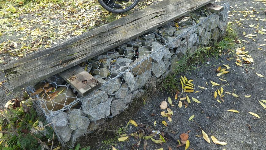 Kaputte Holz-Sitzbank auf gestapelten Steinen am Spree-Rad- und Wanderweg
