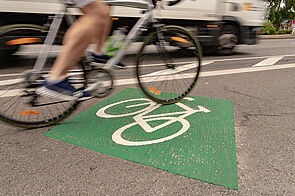 Fahrradpiktogramm mit rautenförmiger Grünbeschichtung auf Radfahrstreifen / Blockpfeil