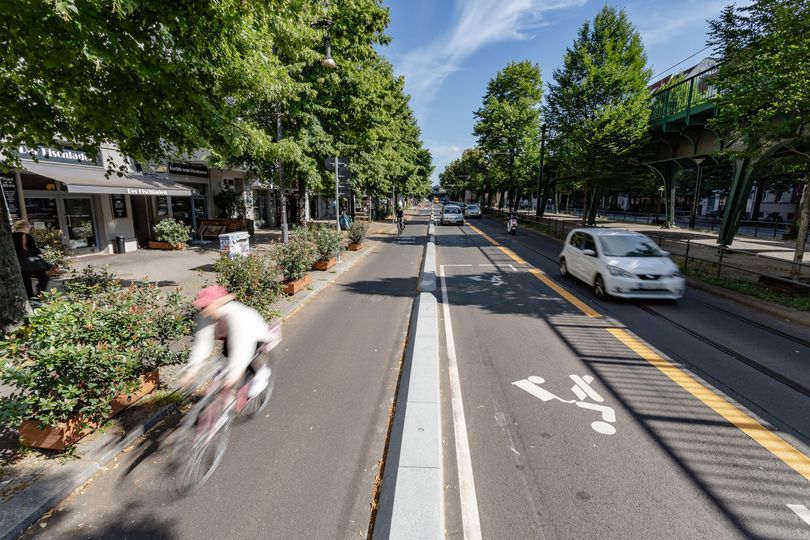 Fahrradfahrer fährt auf einem geschützten Radfahrstreifen. Daneben sieht man eine markierte Lieferzone.