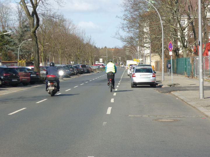 Parkende Autos am Straßenrand und Radfahrender entlang Amrumer Straße