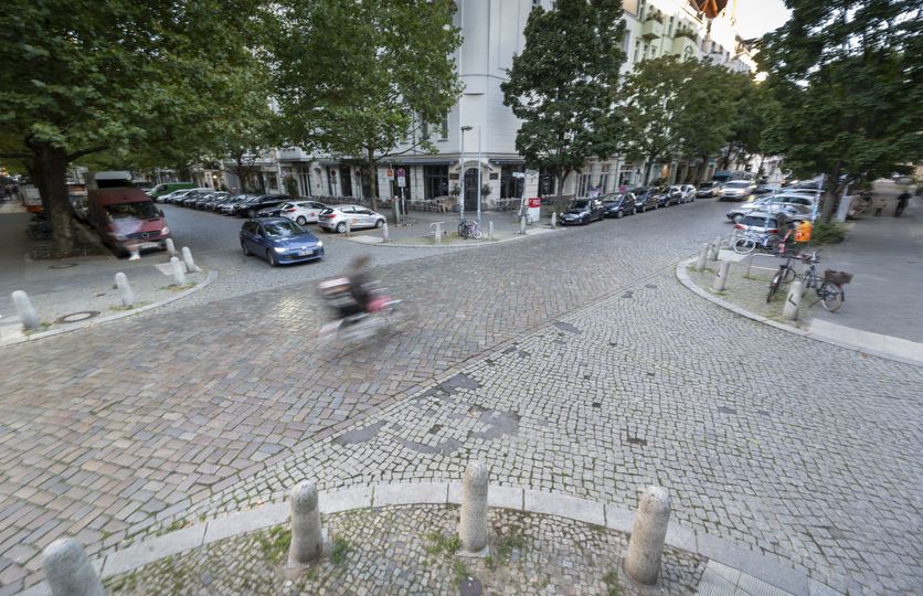 Blick von oben auf eine gepflasterte Straßenkreuzung in Prenzlauer Berg mit Auto- und Radverkehr
