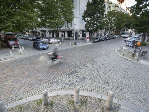 Blick von oben auf eine gepflasterte Straßenkreuzung in Prenzlauer Berg mit Auto- und Radverkehr