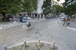 Blick von oben auf eine gepflasterte Straßenkreuzung in Prenzlauer Berg mit Auto- und Radverkehr