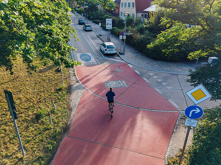 Blick von oben auf die Kreuzung einer Fahrradstraße in einer Wohngegend, auf der ein Fahrradfahrer fährt