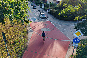 Blick von oben auf die Kreuzung einer Fahrradstraße in einer Wohngegend, auf der ein Fahrradfahrer fährt