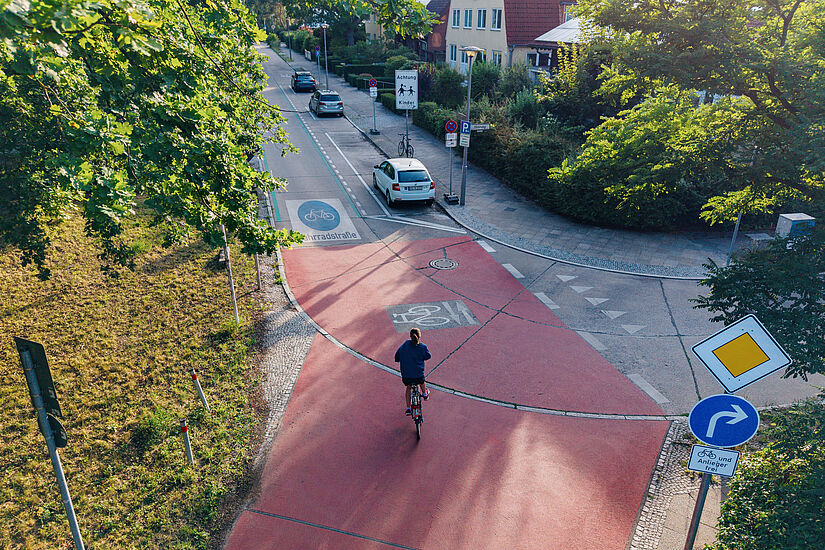 Blick von oben auf die Kreuzung einer Fahrradstraße in einer Wohngegend, auf der ein Fahrradfahrer fährt