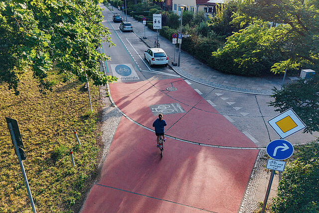 Blick von oben auf die Kreuzung einer Fahrradstraße in einer Wohngegend, auf der ein Fahrradfahrer fährt