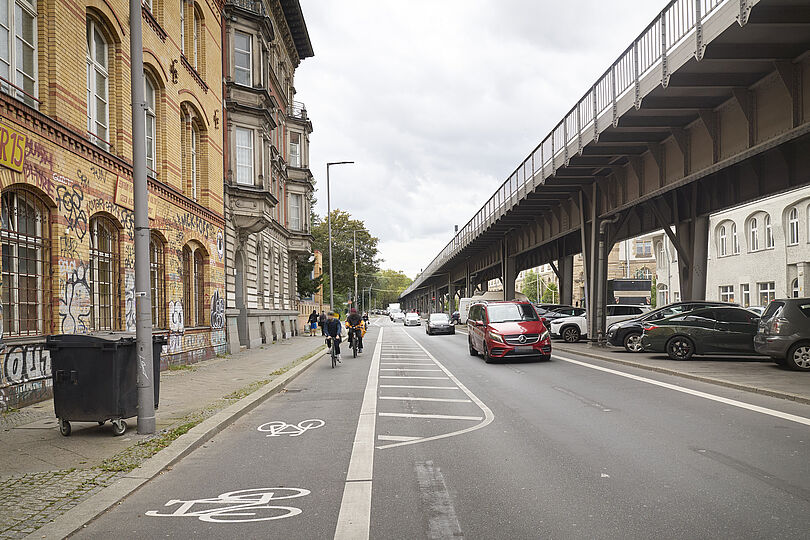 Radfahrstreifen mit Fahrradpiktogrammen, Sicherheitstrennstreifen und Radfahrenden.