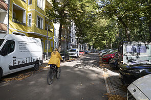 Asphaltierter Straße mit einem Radfahrenden.