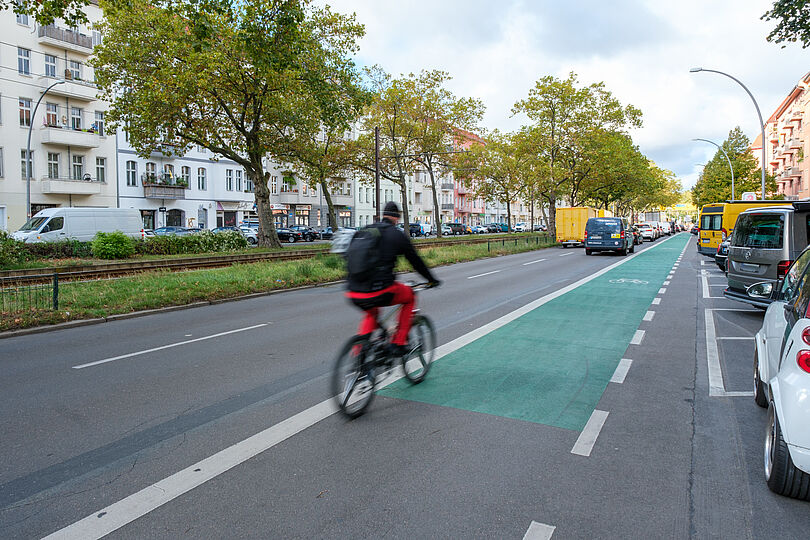 Radfahrstreifen auf der Danziger Straße, der grün und mit Abstand zu den parkenden Autos markiert ist.