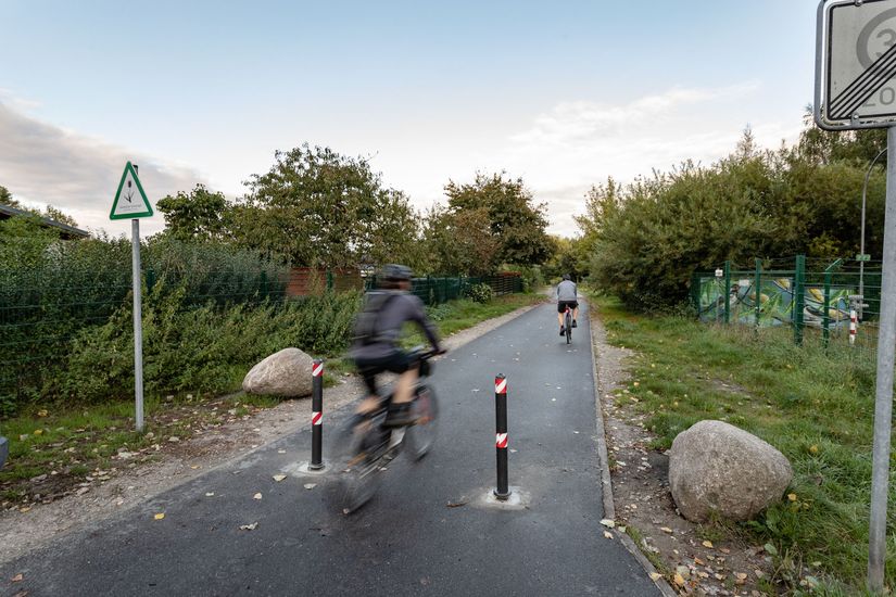 Radfahrende auf asphaltiertem Rad- und Fußweg durch Felder