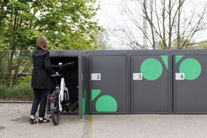 Frau schiebt ein e-Bike in eine Fahrradbox hinein
