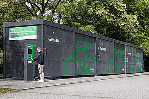 Ein Mann bedient dasTerminal einer gesicherten Fahrradabstellanlage.