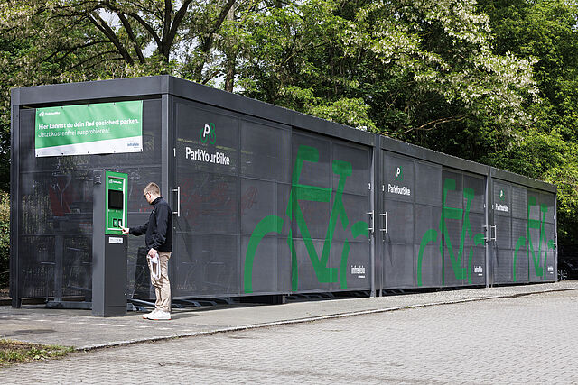 Ein Mann bedient dasTerminal einer gesicherten Fahrradabstellanlage.