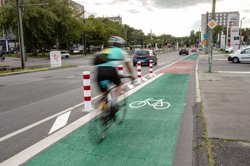 Radfahrerin auf farblich markiertem Radfahrstreifen mit Protektionselementen