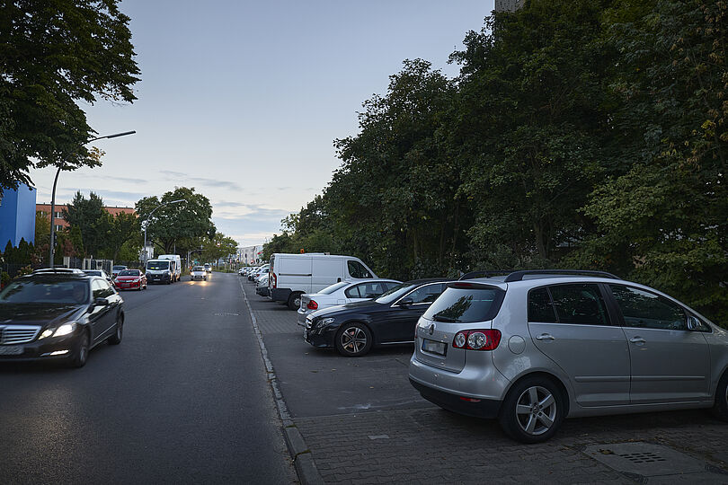 Autostraße mit Querparkplätzen an der rechten Straßenrand.