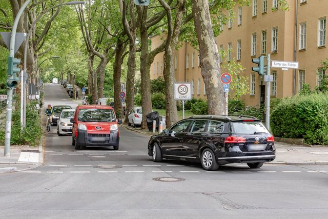 Stadtstraße mit viel Autoverkehr, Radfahrer fährt zwischen Autos und Fahrbahnrand