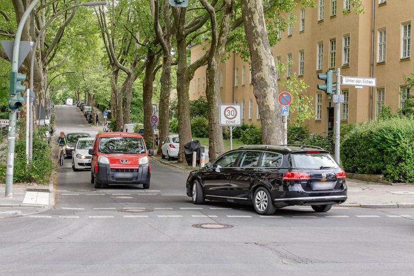 Stadtstraße mit viel Autoverkehr, Radfahrer fährt zwischen Autos und Fahrbahnrand