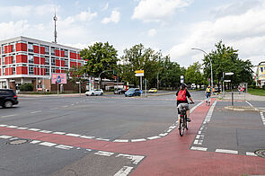 Radfahrerin fährt über Kreuzung mit rot markiertem Radstreifen