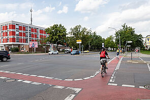 Radfahrerin fährt über Kreuzung mit rot markiertem Radstreifen