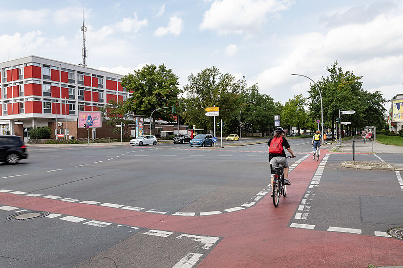 Radfahrerin fährt über Kreuzung mit rot markiertem Radstreifen